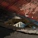 Reflection of a modern architectural building in a sidewalk puddle with textured surfaces.