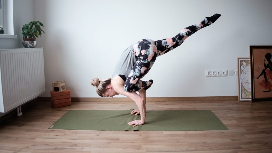 a woman doing a handstand on a yoga mat