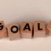 Aligned wooden blocks spelling 'Goals' symbolize target achievement and ambition.